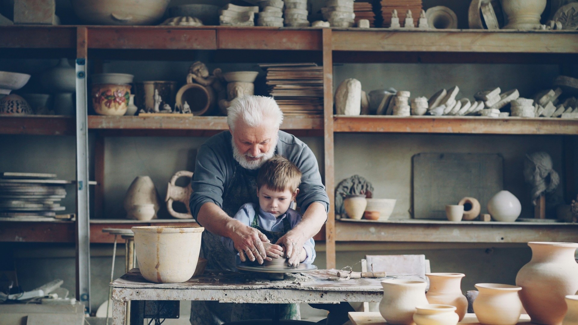 Grandfather teaching grandson pottery